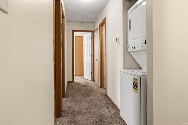 washroom featuring a textured ceiling, carpet flooring, and stacked washer and clothes dryer