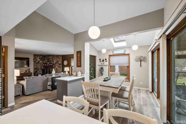 dining area featuring vaulted ceiling with skylight, a fireplace, and hardwood / wood-style flooring