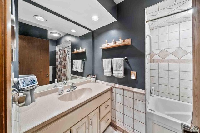 bathroom with shower / bath combo, vanity, and tile walls