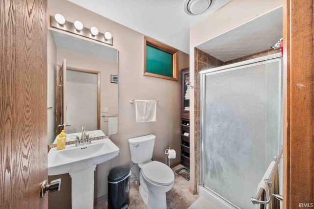 bathroom with a shower with shower door and toilet