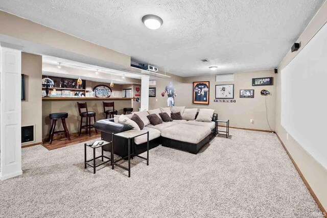 living room featuring light carpet, bar area, and a textured ceiling