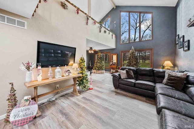 living room featuring ceiling fan, hardwood / wood-style floors, and a towering ceiling