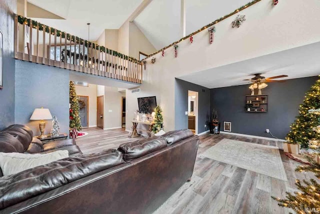 living room with ceiling fan, high vaulted ceiling, and wood-type flooring