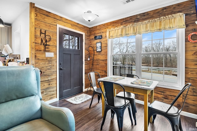 dining area with dark hardwood / wood-style floors and wooden walls