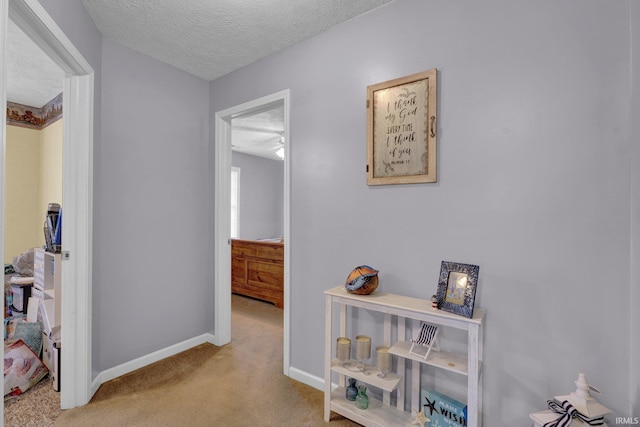 corridor featuring light carpet and a textured ceiling