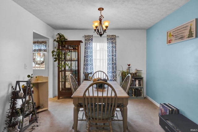 carpeted dining area featuring a textured ceiling and an inviting chandelier