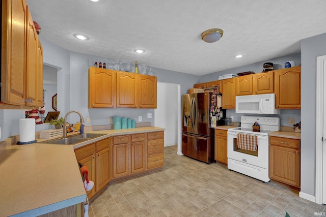 kitchen featuring a textured ceiling, white appliances, and sink