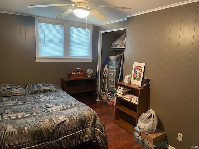 bedroom featuring ceiling fan, dark hardwood / wood-style floors, ornamental molding, and wooden walls