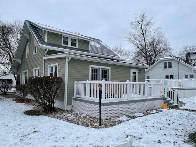 snow covered rear of property featuring a wooden deck