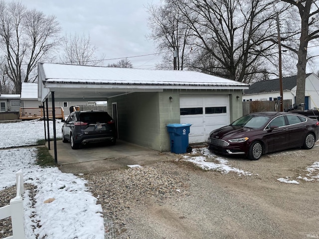 snow covered garage with a carport