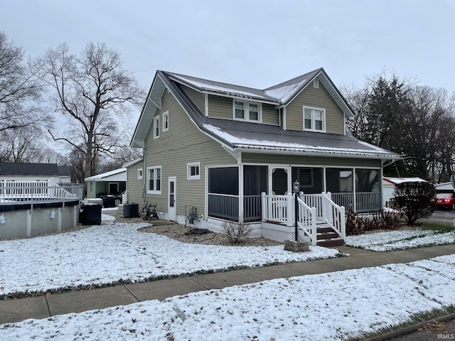 view of front of house with central AC and a sunroom