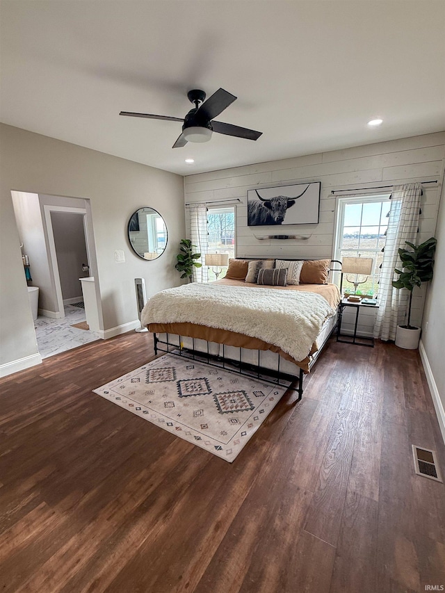 bedroom with ceiling fan, dark hardwood / wood-style flooring, and wood walls