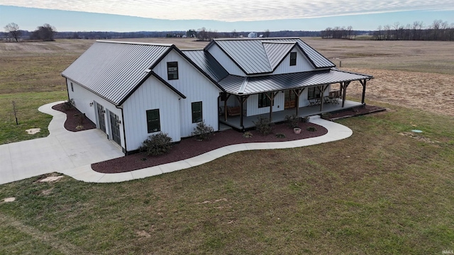 rear view of property featuring a porch, a yard, a rural view, and a garage