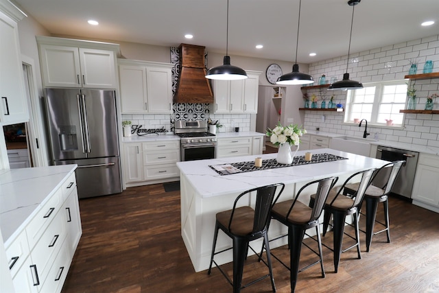 kitchen with a center island, white cabinets, wall chimney range hood, sink, and stainless steel appliances