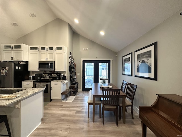 dining room with french doors, high vaulted ceiling, and light hardwood / wood-style flooring