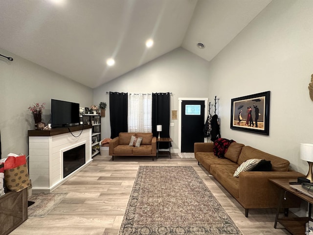 living room with light hardwood / wood-style floors and high vaulted ceiling