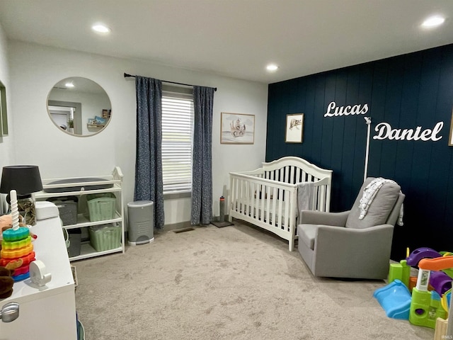 bedroom with a crib, carpet floors, and wooden walls