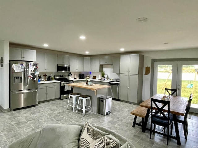 kitchen featuring butcher block countertops, a kitchen breakfast bar, gray cabinetry, and stainless steel appliances