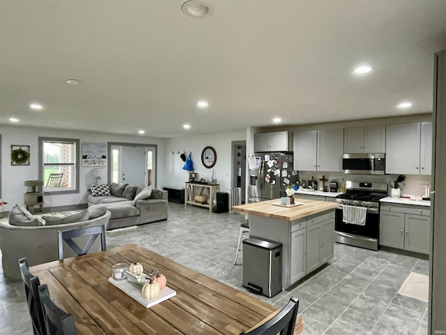 kitchen with appliances with stainless steel finishes, a center island, butcher block countertops, and gray cabinetry