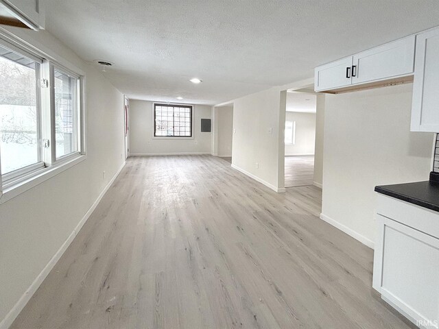 unfurnished living room featuring light wood-type flooring and a textured ceiling