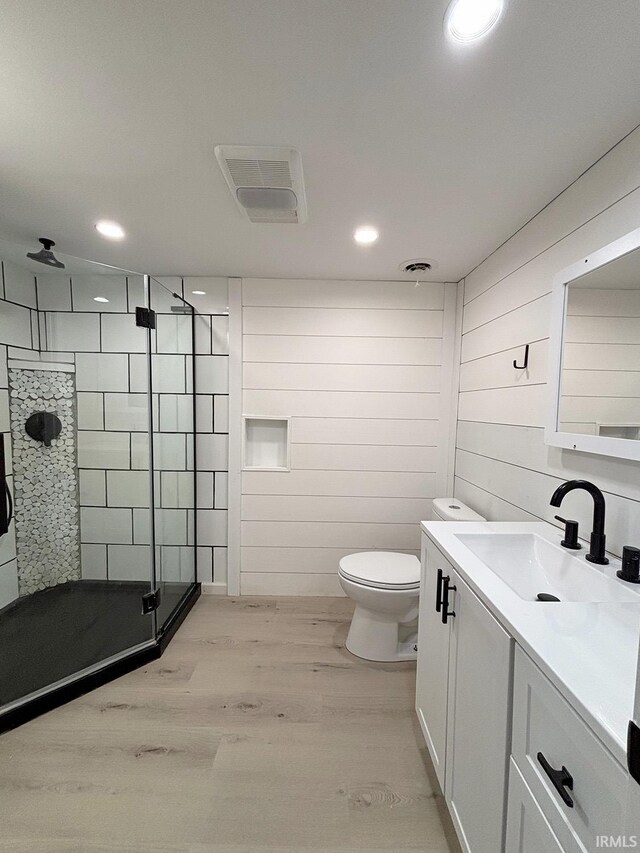 bathroom featuring toilet, vanity, a shower with shower door, and hardwood / wood-style flooring