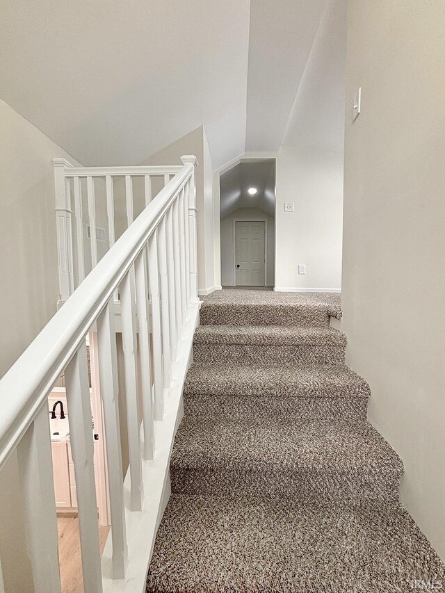 stairs with carpet flooring and lofted ceiling