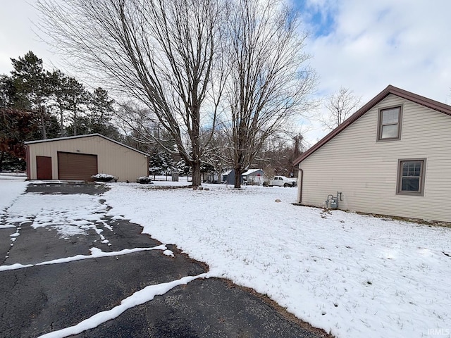 yard layered in snow with an outbuilding and a garage