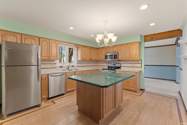 kitchen featuring sink, a center island, stainless steel appliances, a notable chandelier, and decorative light fixtures