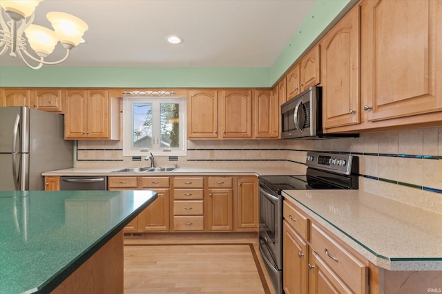 kitchen featuring sink, hanging light fixtures, stainless steel appliances, an inviting chandelier, and light hardwood / wood-style floors