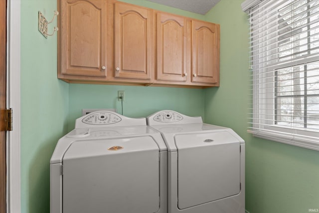 clothes washing area with washer and dryer, cabinets, and a textured ceiling