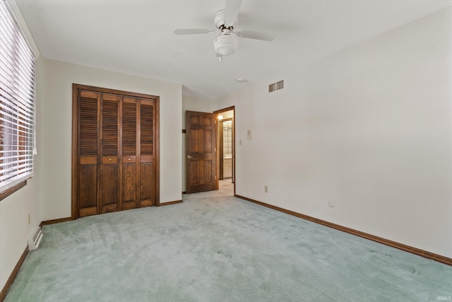 unfurnished bedroom with light carpet, a closet, a baseboard radiator, and ceiling fan