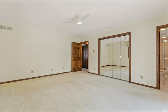 unfurnished bedroom with a closet, ensuite bathroom, ceiling fan, and light colored carpet