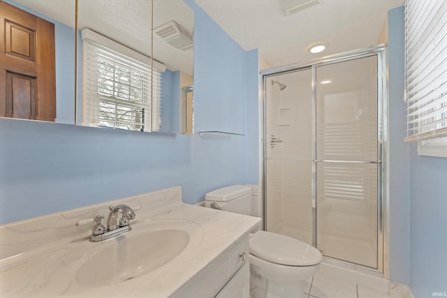 bathroom featuring tile patterned flooring, vanity, toilet, and a shower with shower door