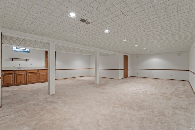 basement featuring light colored carpet and sink