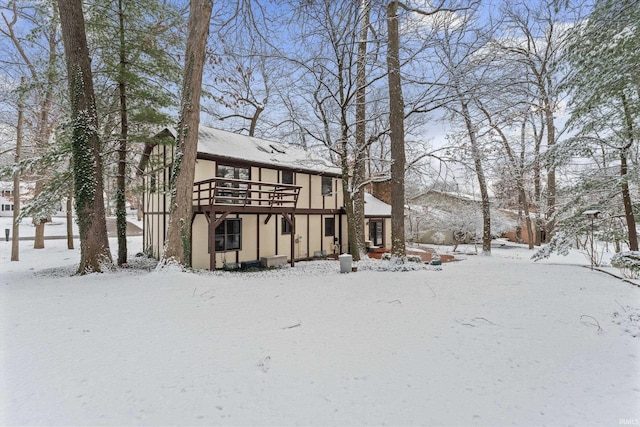 snow covered back of property featuring a wooden deck