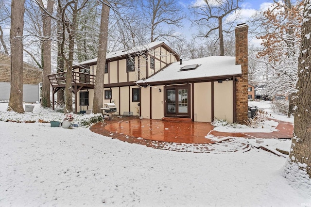 snow covered house featuring a wooden deck and french doors