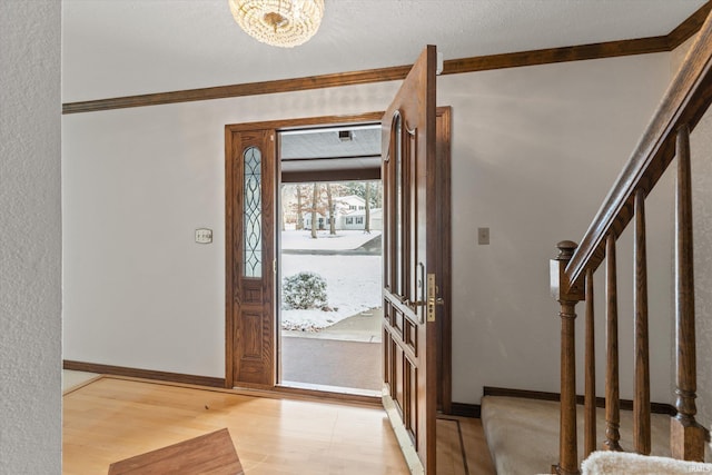 foyer entrance featuring ornamental molding, light hardwood / wood-style floors, and an inviting chandelier