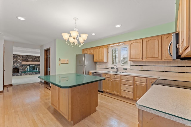 kitchen with an inviting chandelier, decorative light fixtures, a fireplace, a kitchen island, and appliances with stainless steel finishes