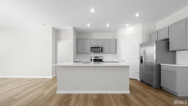 kitchen featuring light countertops, appliances with stainless steel finishes, and an island with sink