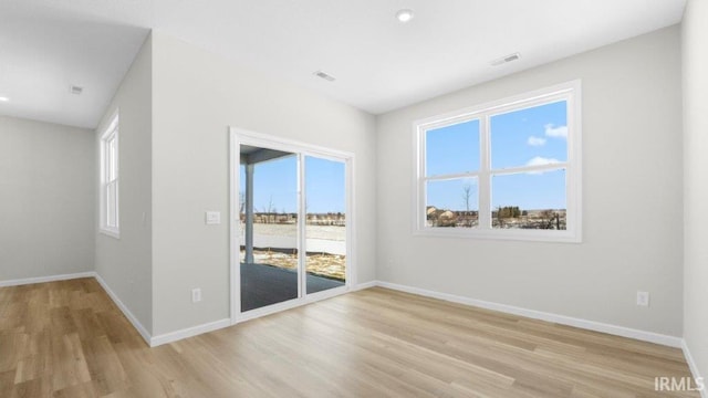 unfurnished room with light wood-style flooring, visible vents, and baseboards