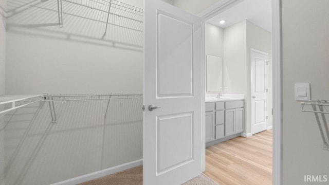 spacious closet featuring a sink and light wood-style floors
