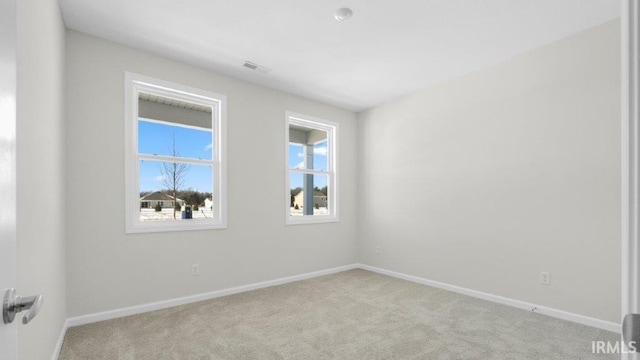 empty room featuring light carpet, visible vents, and baseboards