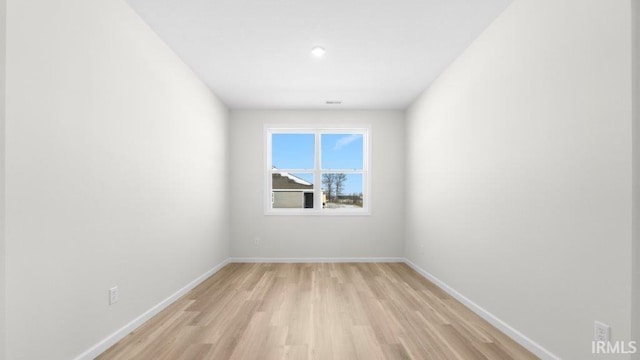 spare room featuring baseboards, visible vents, and light wood-style floors