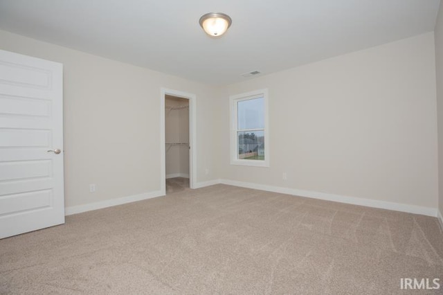 unfurnished bedroom with light carpet, a spacious closet, and a closet