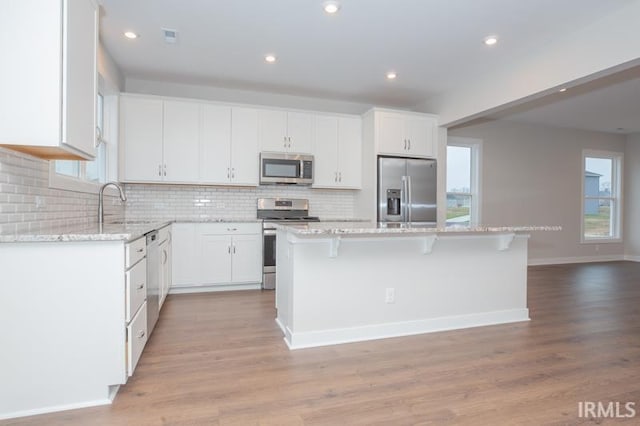 kitchen with white cabinets, decorative backsplash, a center island, and appliances with stainless steel finishes