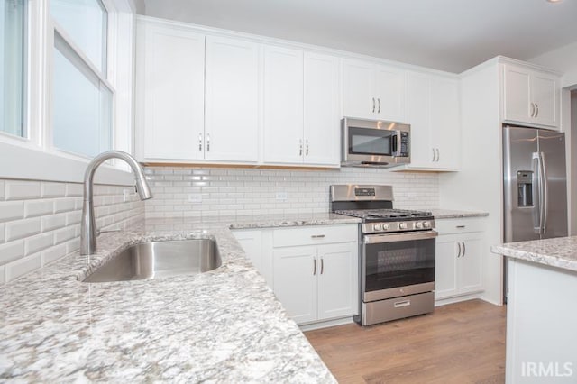 kitchen with white cabinets, backsplash, sink, and stainless steel appliances