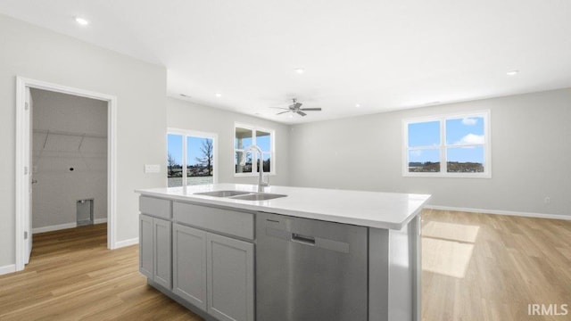 kitchen featuring a kitchen island with sink, gray cabinetry, a sink, light countertops, and dishwasher