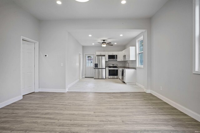 unfurnished living room with ceiling fan, sink, and light hardwood / wood-style flooring