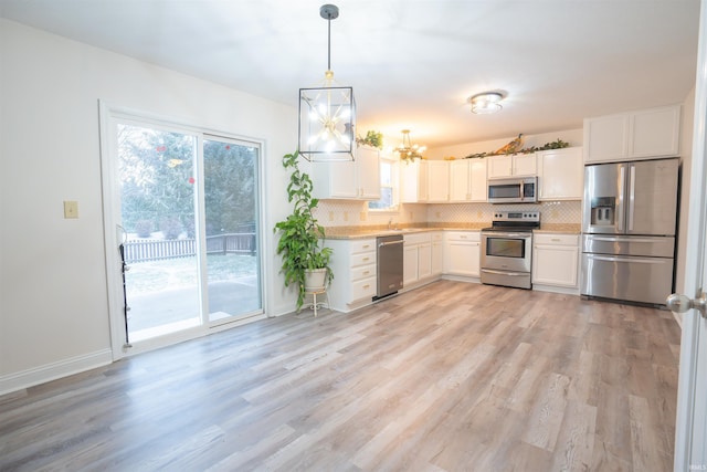 kitchen with backsplash, white cabinets, light wood-type flooring, decorative light fixtures, and stainless steel appliances