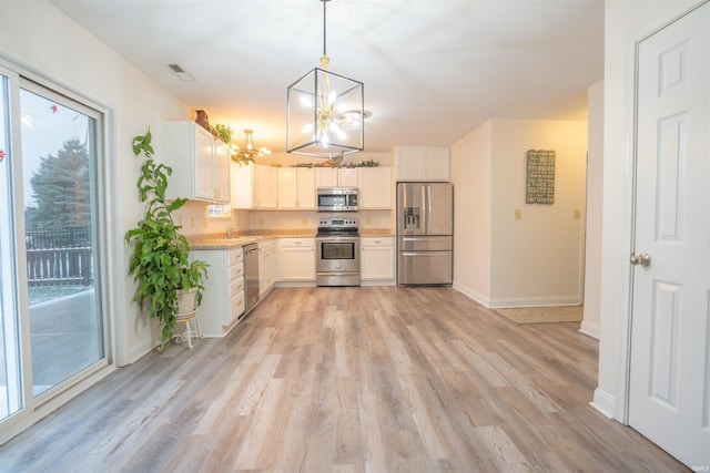 kitchen with white cabinets, appliances with stainless steel finishes, backsplash, and decorative light fixtures